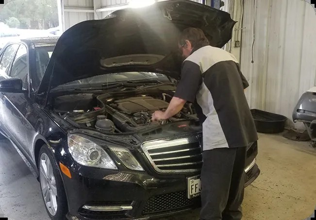 A Dearing technician working under the hood of a Mercedes-Benz E-Class